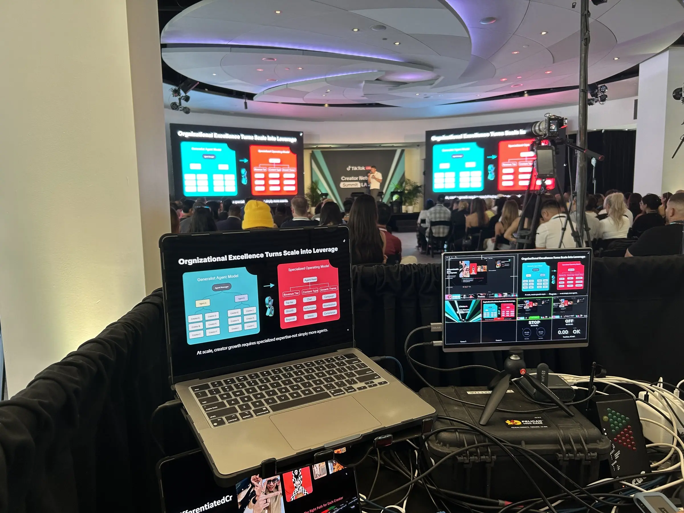 A laptop and a control monitor in the foreground with the stage screens running slides beyond.