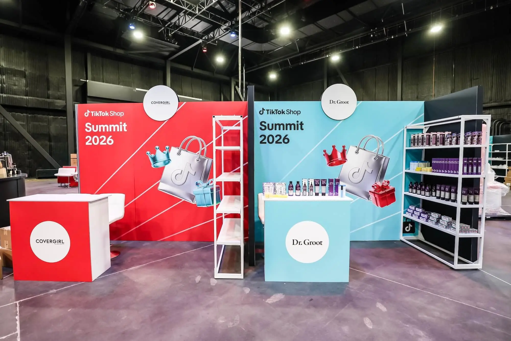 Two exhibitor booths side by side in the hall, one red and one blue, with product shelving and Summit 2026 headers above them.